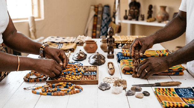 Hands threading heritage beads over kente cloth
